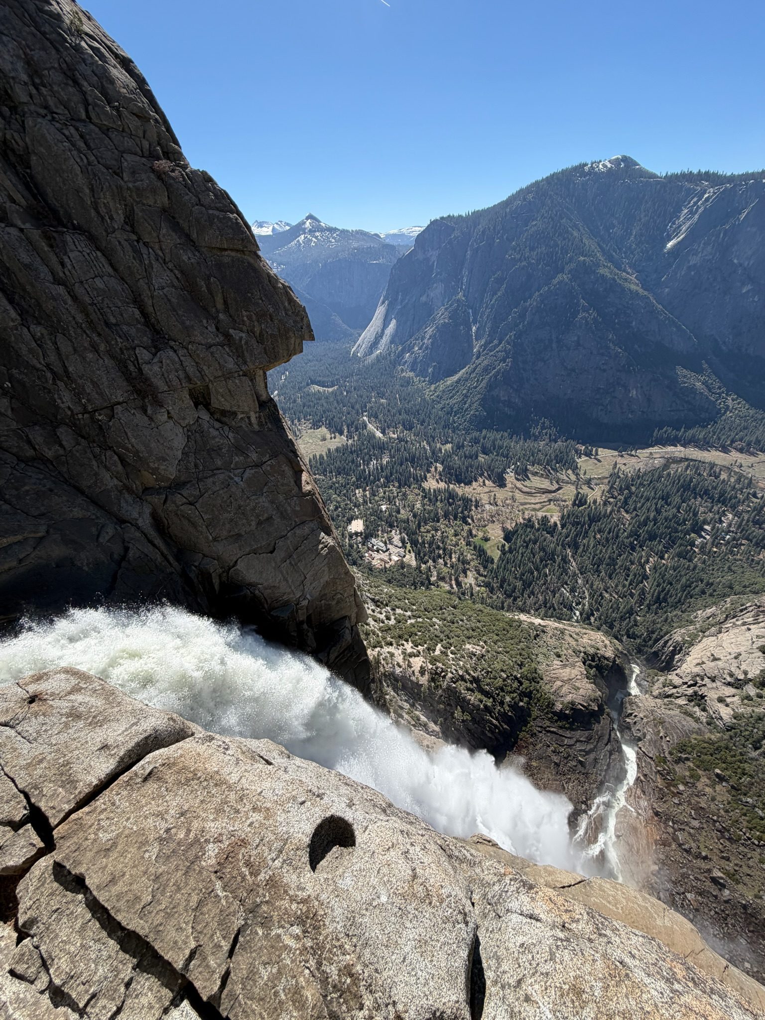 Whitewater pouring over the granite lip at the top of Yosemite Falls, with Yosemite Valley far below.